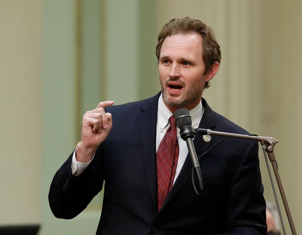 Assemblyman James Gallagher speaking at a podium with a microphone.
