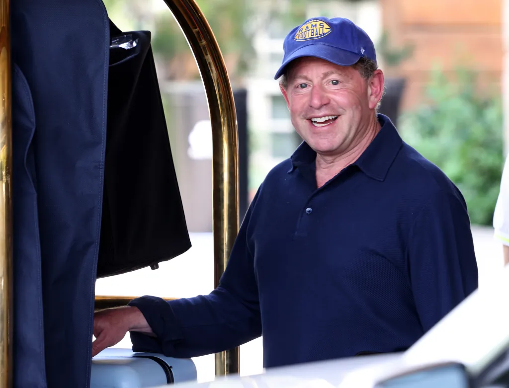 CEO of Activision Blizzard, Bobby Kotick, smiles, wearing a blue polo shirt and a blue cap with a yellow 