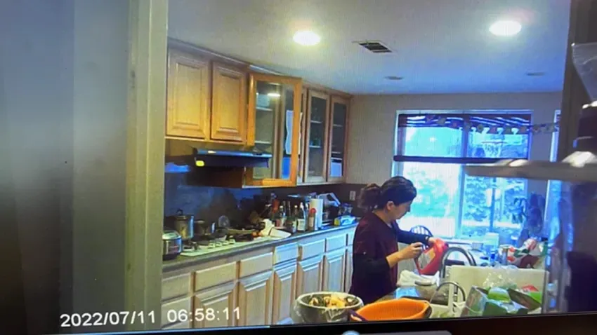 Surveillance footage of a woman pouring Drano into a beverage in a kitchen.