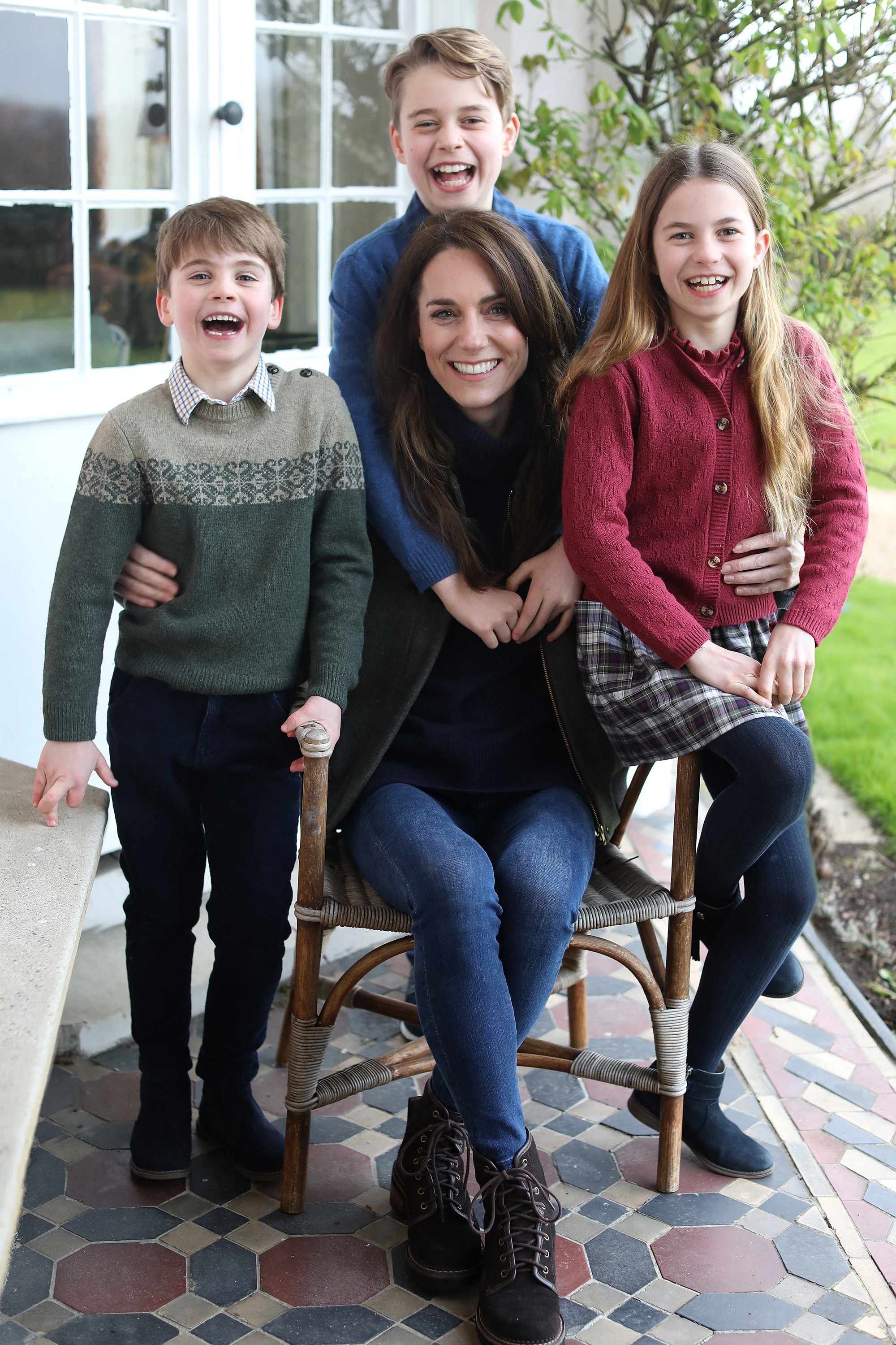 The Princess of Wales with her children, Prince Louis, Prince George, and Princess Charlotte, smiling on a porch.