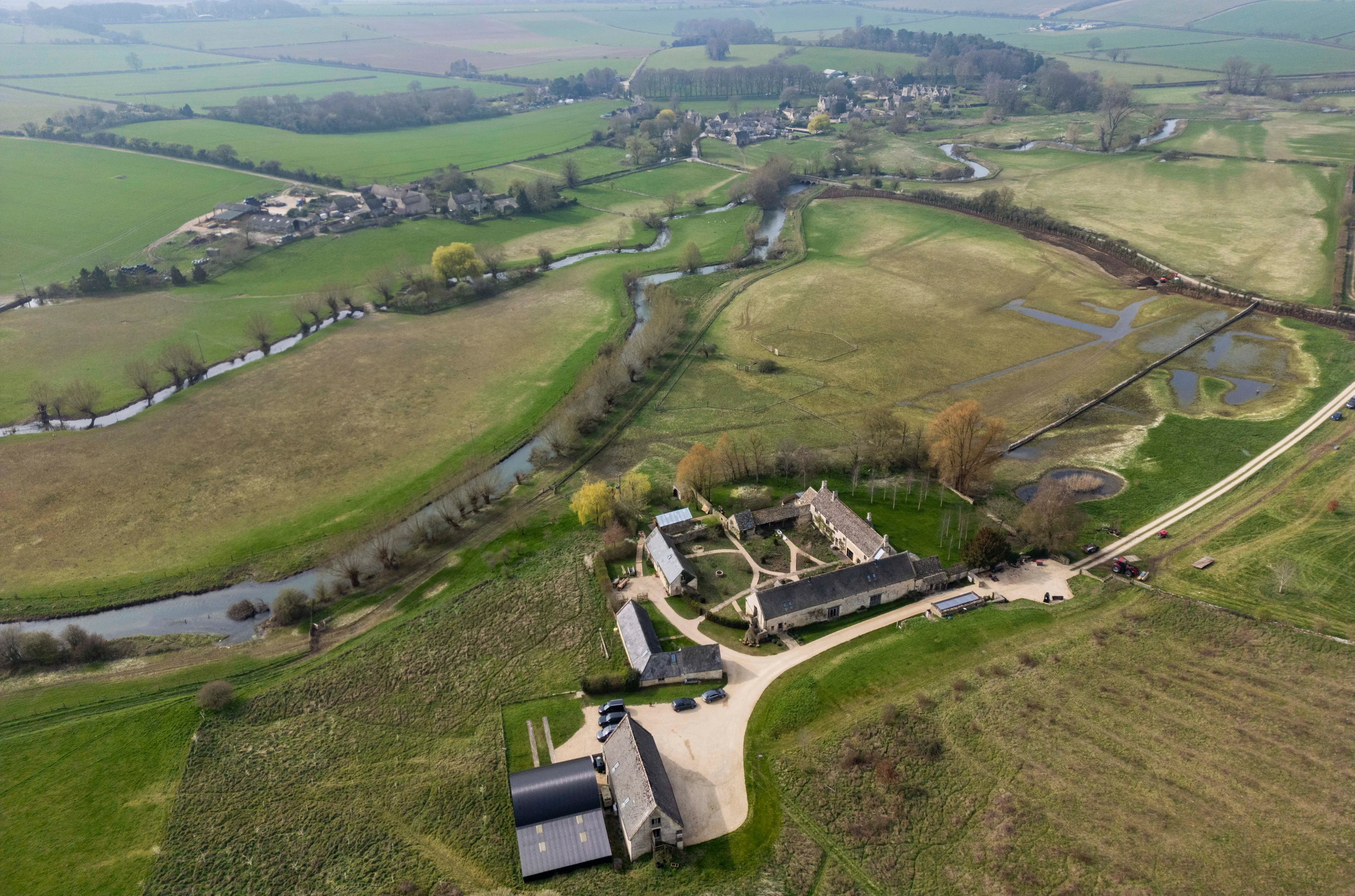 Aerial view of Ellen DeGeneres and Portia De Rossi's Cotswolds estate, showing the buildings, surrounding fields, and the River Windrush.