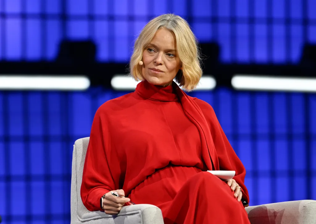Katherine Maher, CEO of NPR, in a red dress on stage at the Web Summit conference.