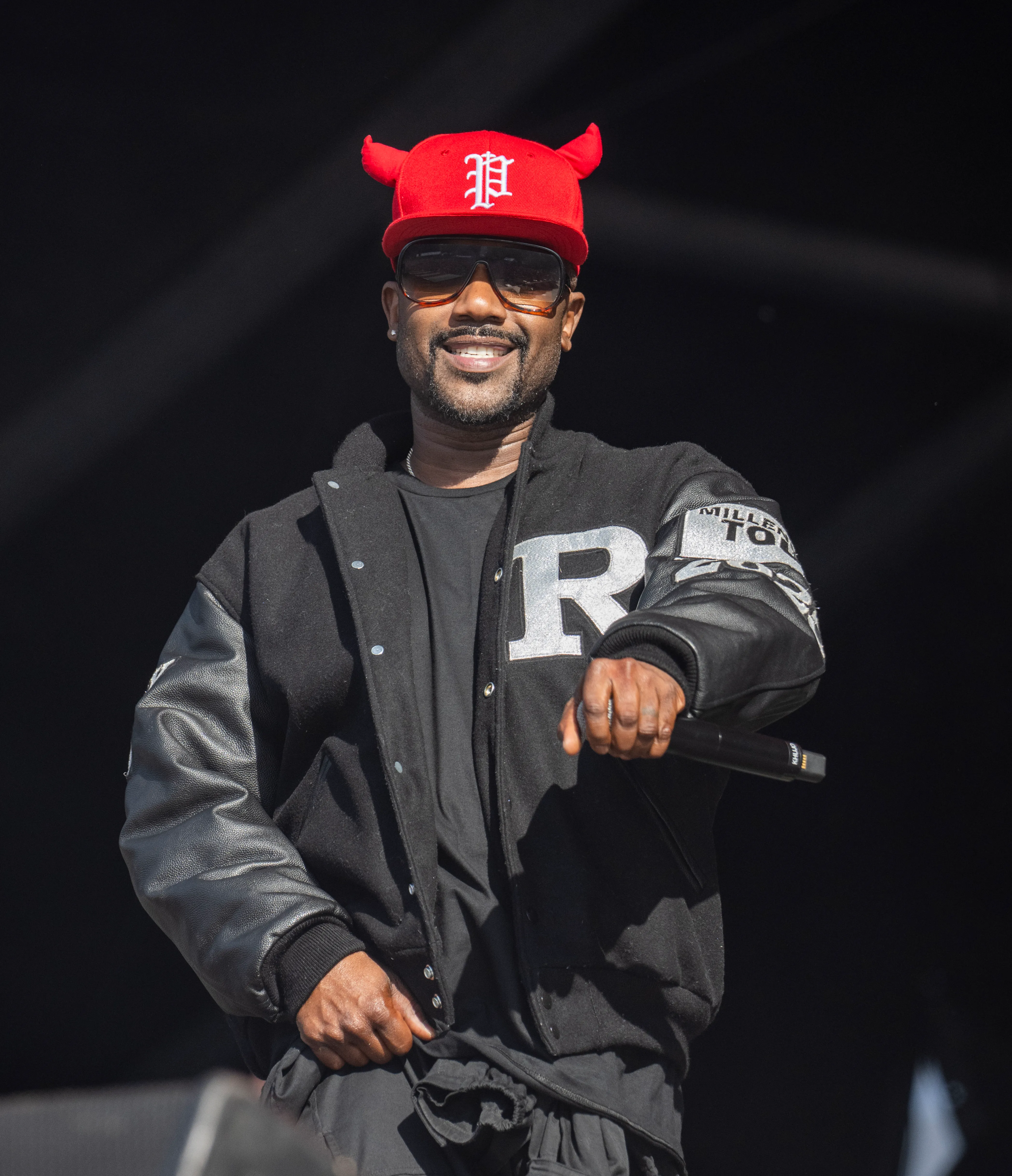 Ray J performing onstage in a black and red outfit with a microphone in hand.