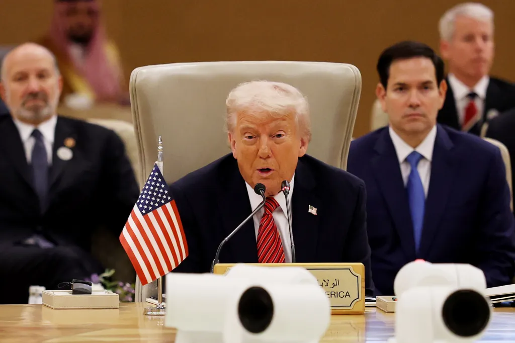 President Donald Trump speaking at the Gulf Cooperation Council Leaders’ Summit with an American flag and microphones in front of him.