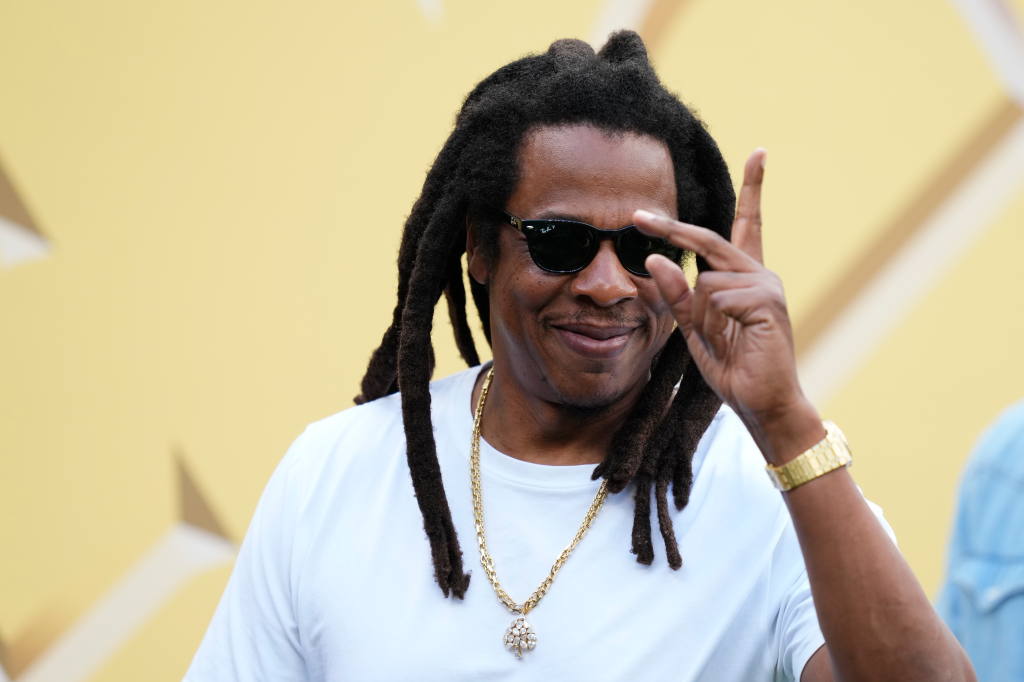 Rapper Jay-Z smiling, wearing sunglasses and making a hand gesture, prior to the FIFA Club World Cup 2025 semi-final match.