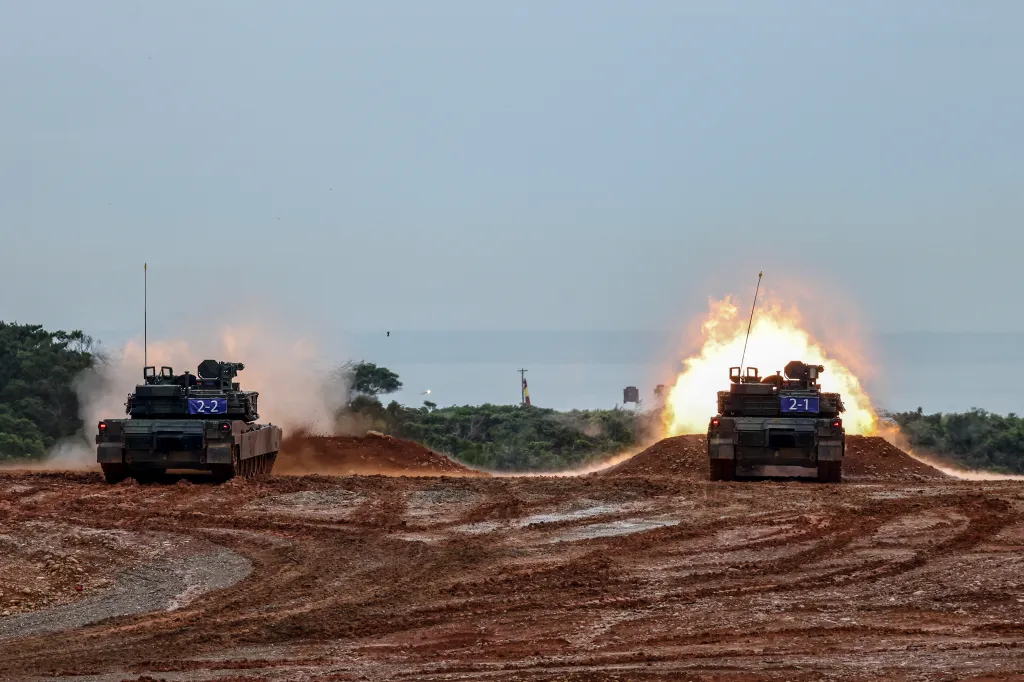 Two M1A2T Abrams tanks fire live rounds on a muddy firing range in Taiwan.