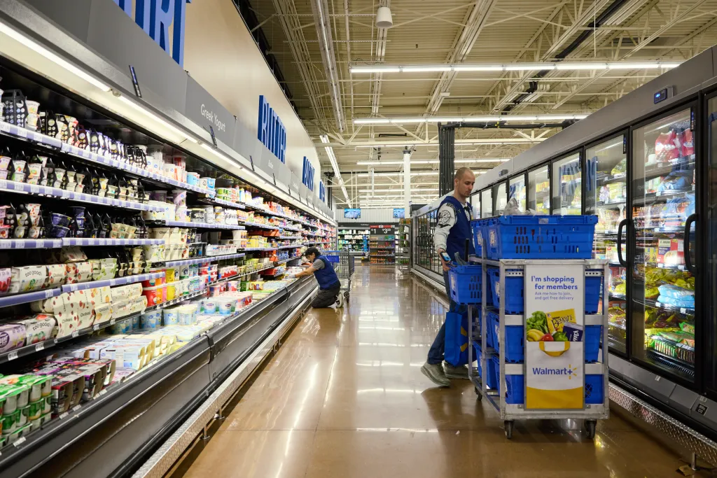 Two workers stocking shelves in a Walmart grocery aisle on Black Friday.