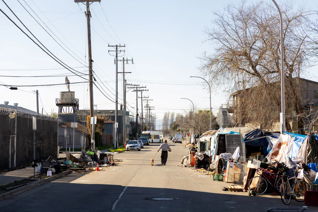 An encampment of tents and various belongings piled high along a street in Berkeley, California.