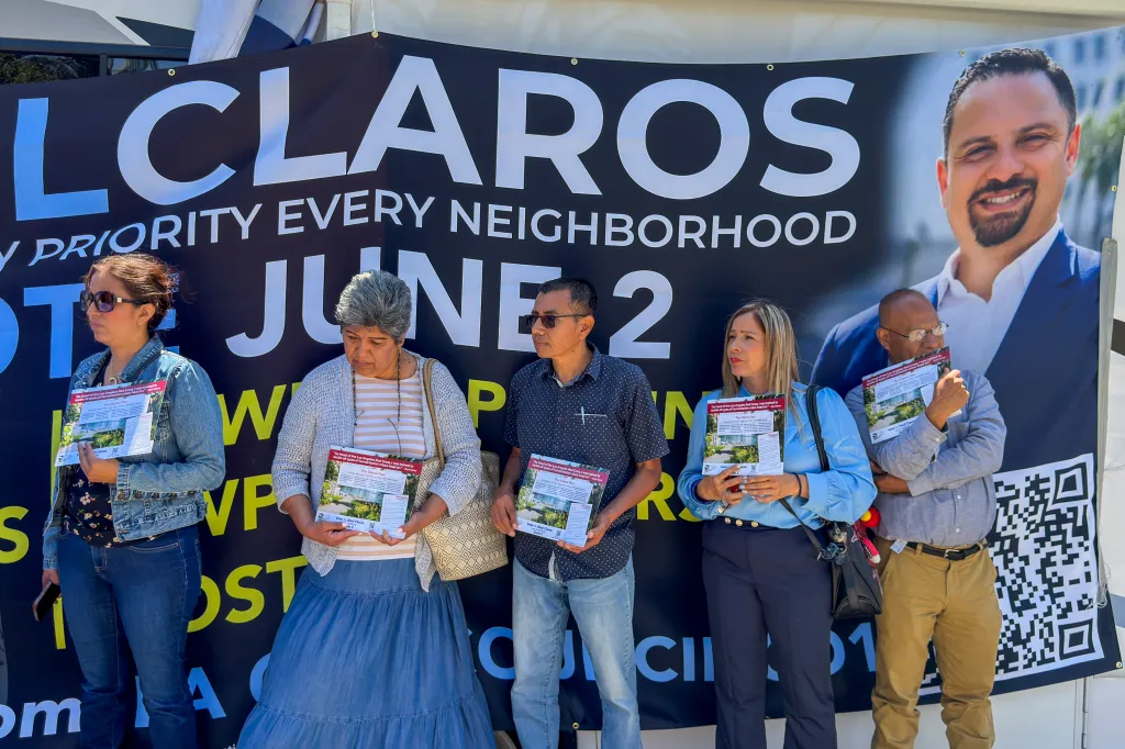 Los Angeles City Council candidate Raúl Claros with supporters holding campaign flyers at a news conference.