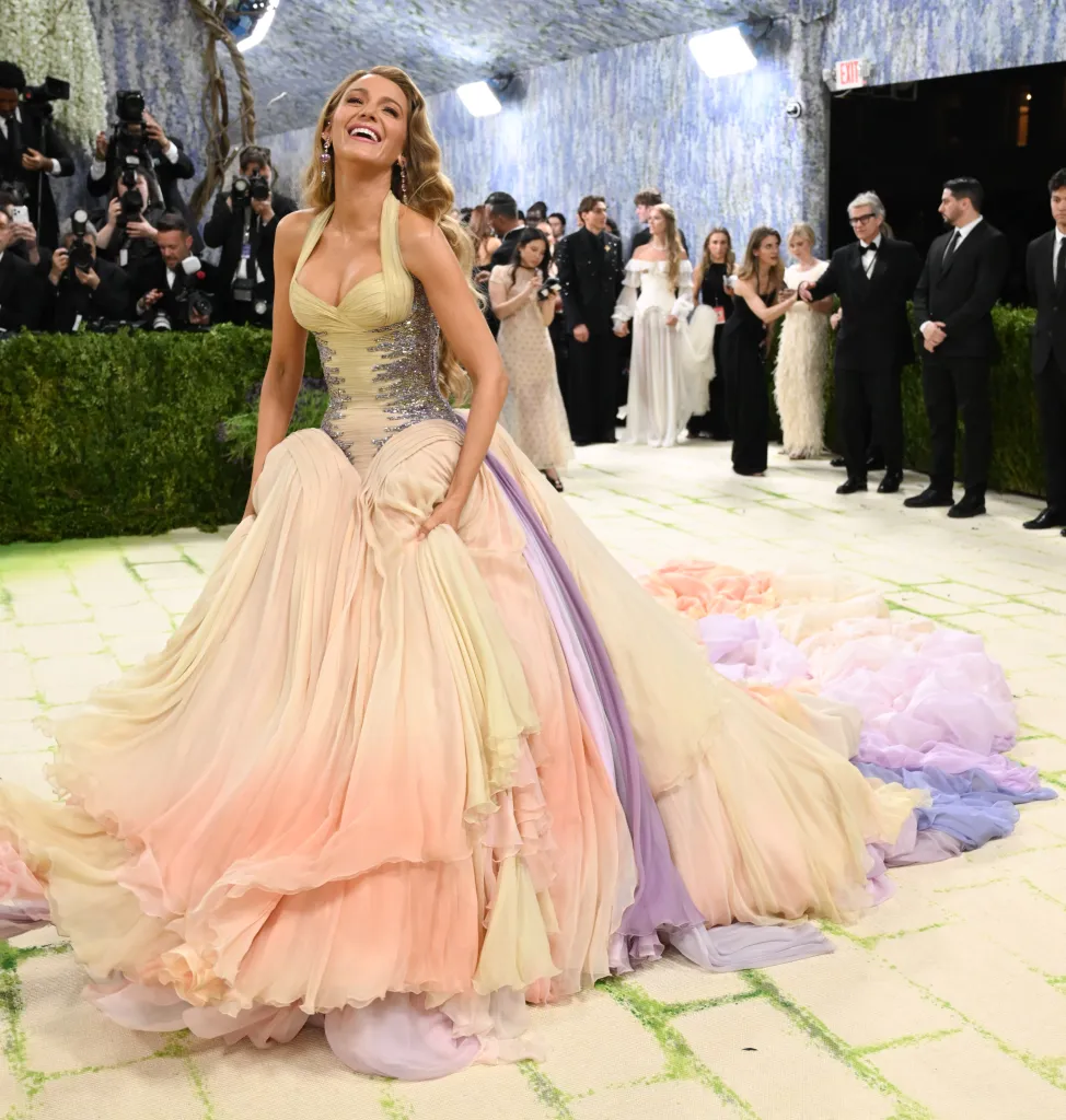 Blake Lively smiling in a flowing, multicolored gown at the Met Gala.