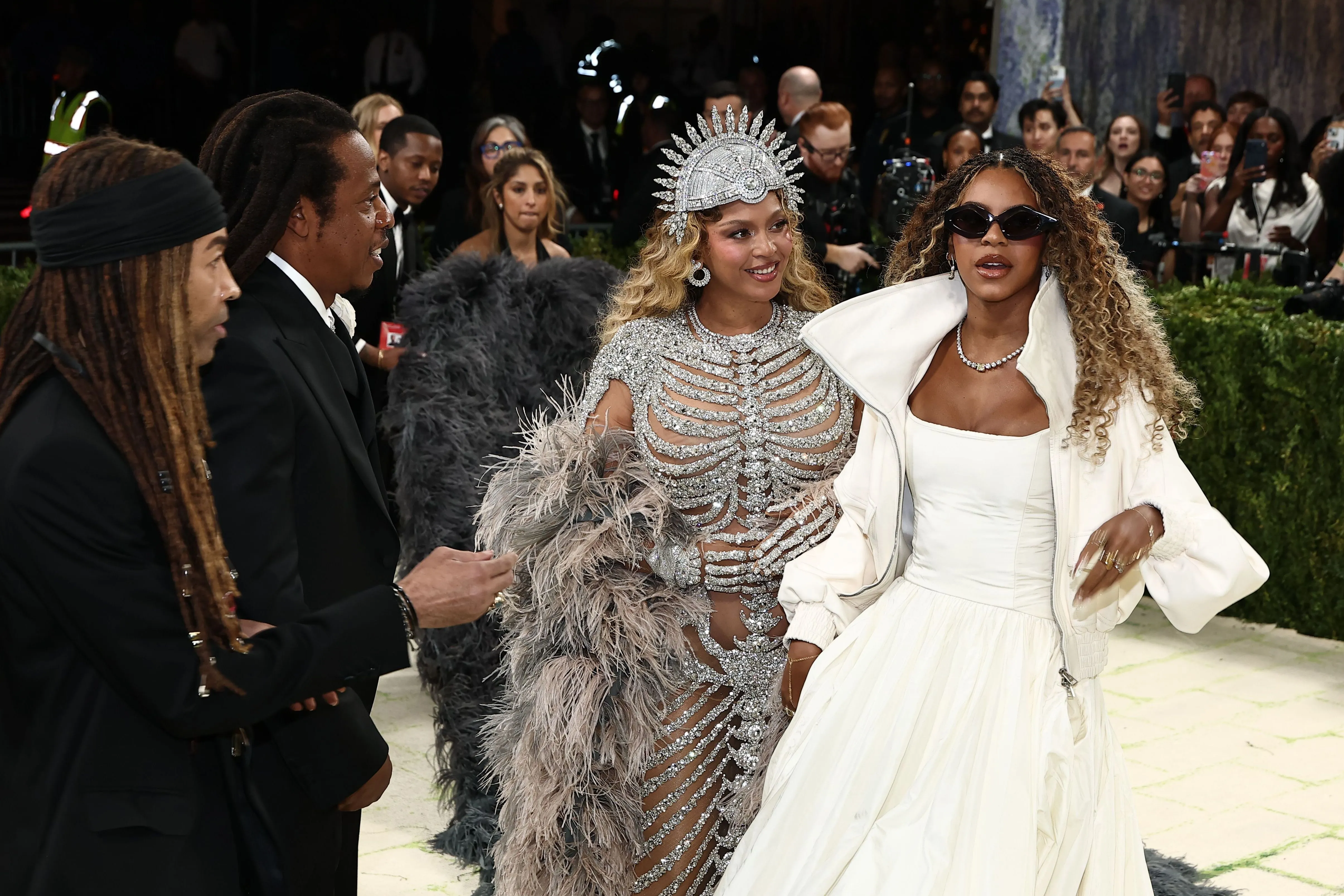 Beyonce in a silver bejeweled gown and elaborate headpiece, Blue Ivy Carter in a white dress and jacket, and Jay-Z in a suit, arriving at the Met Gala.