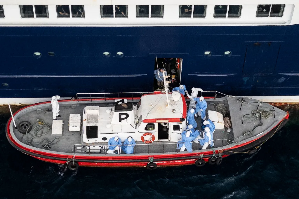 Aerial view of health personnel assisting patients from a cruise ship onto a boat.