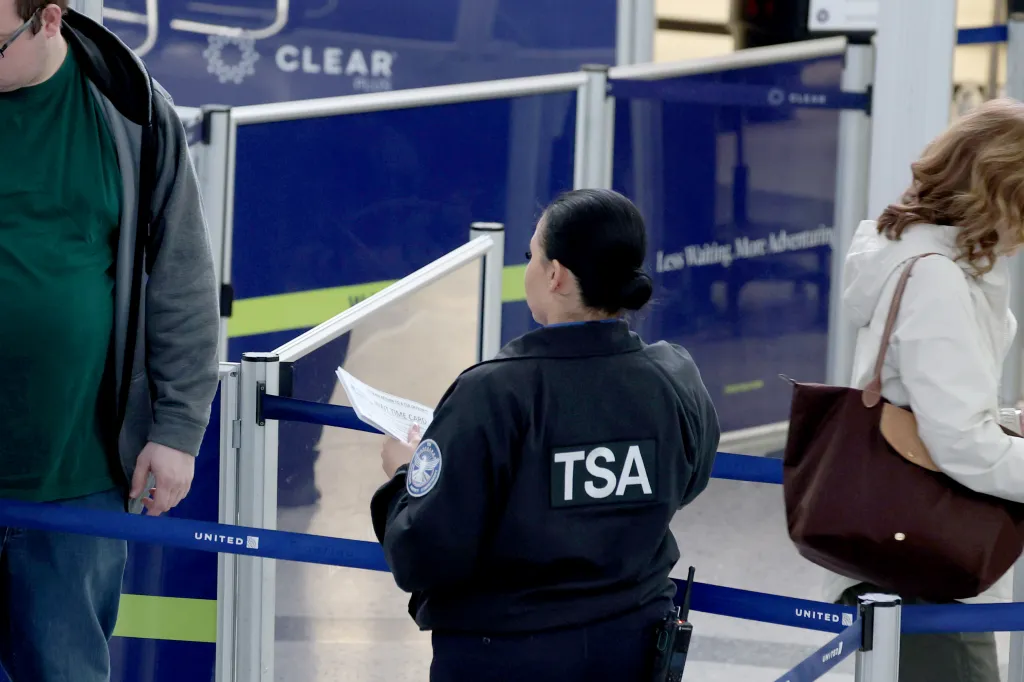 A TSA officer at Newark Airport holding a Wait Time Card.