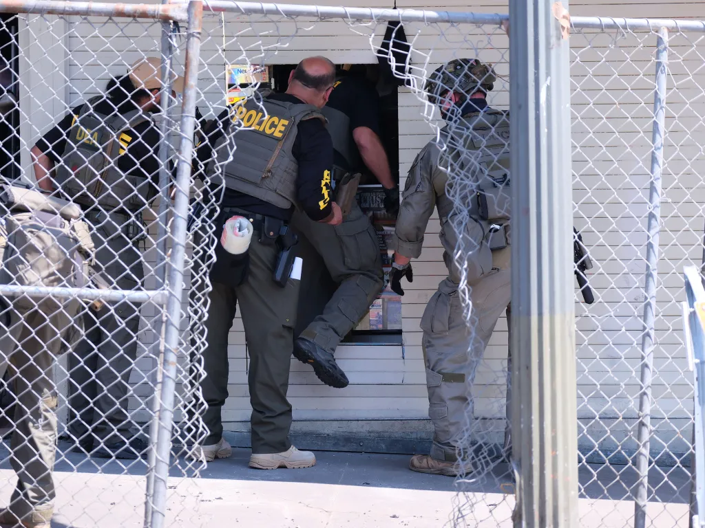 Law enforcement officers and DEA agents entering a building during raids at MacArthur Park.
