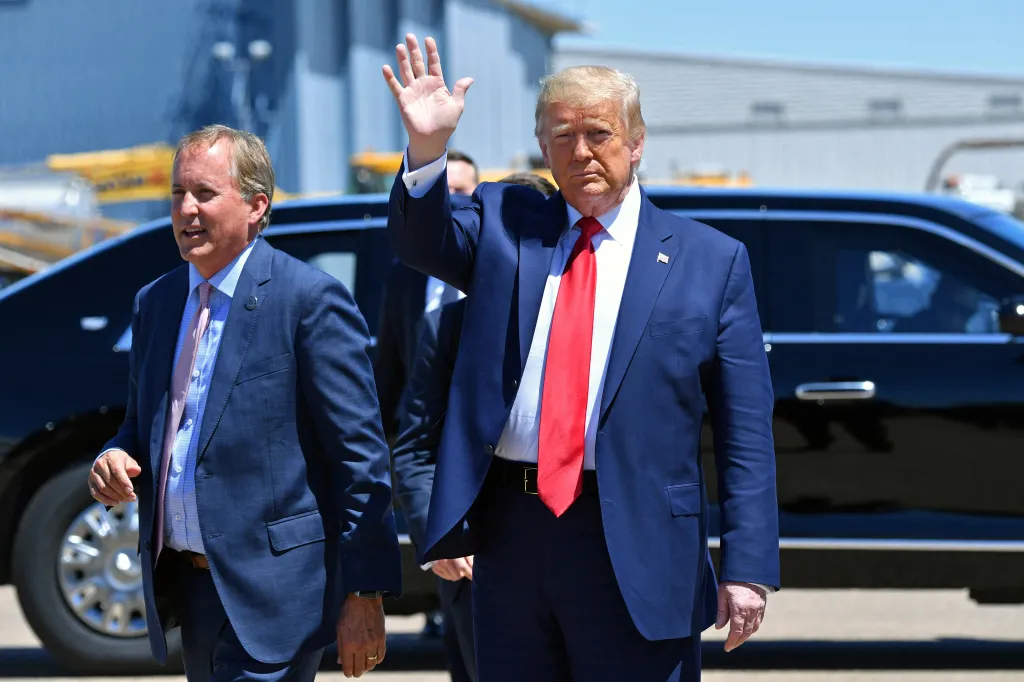 Donald Trump waving while walking beside Ken Paxton.