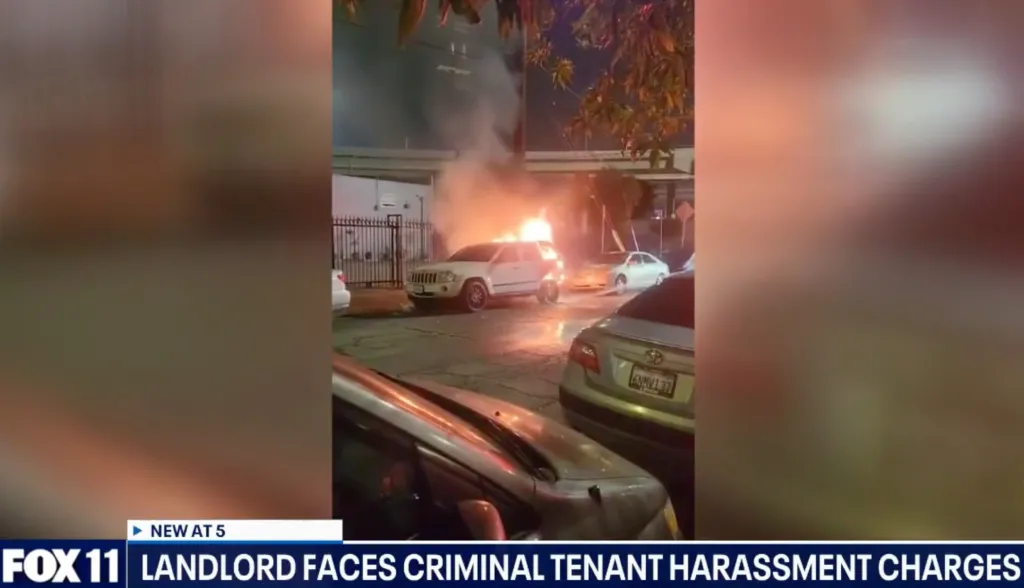 White SUV on fire in a city street at night, with several other cars parked nearby.