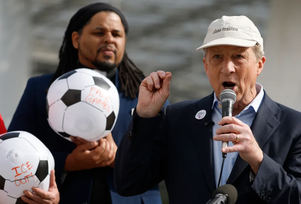 California Democratic gubernatorial candidate Tom Steyer speaking at a union protest, with a man behind him holding a soccer ball with 