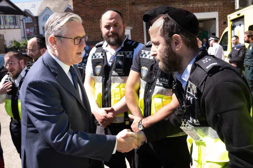 Britain's Prime Minister Keir Starmer shaking hands with a Shomrim North West London first responder during a visit to Golders Green.