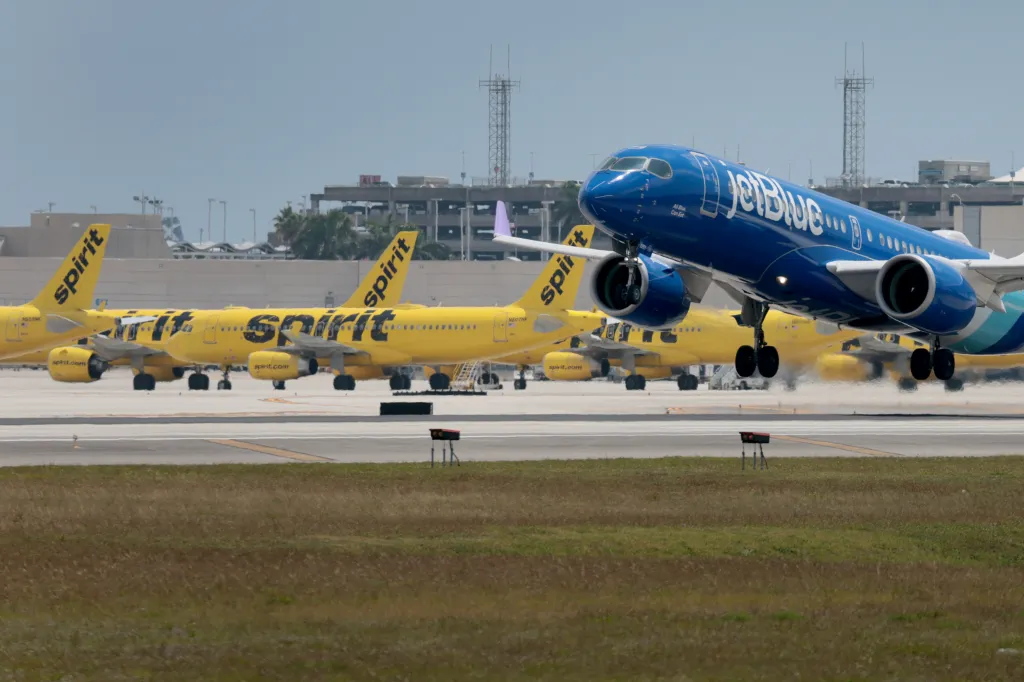 A JetBlue flight takes off in front of a group of Spirit Airline planes on May 2, 2026.