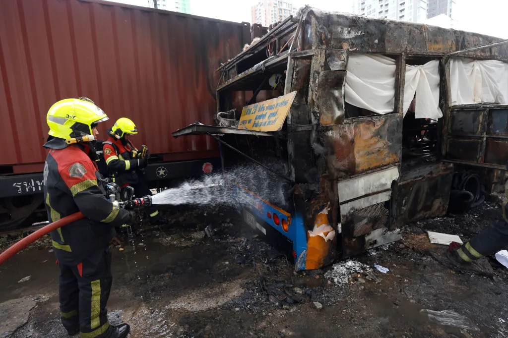 Thai rescue workers extinguishing a fire on a public bus that collided with a freight train in Bangkok.