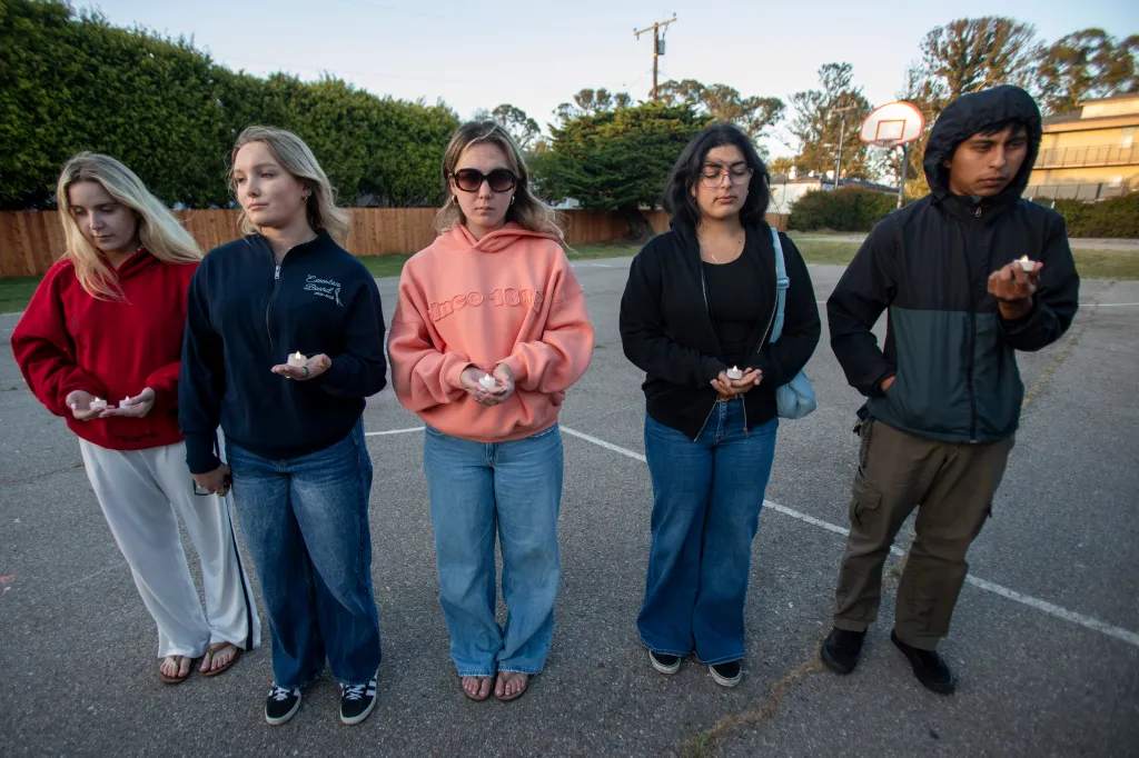 Five college students holding candles during a vigil honoring a sexual assault survivor.