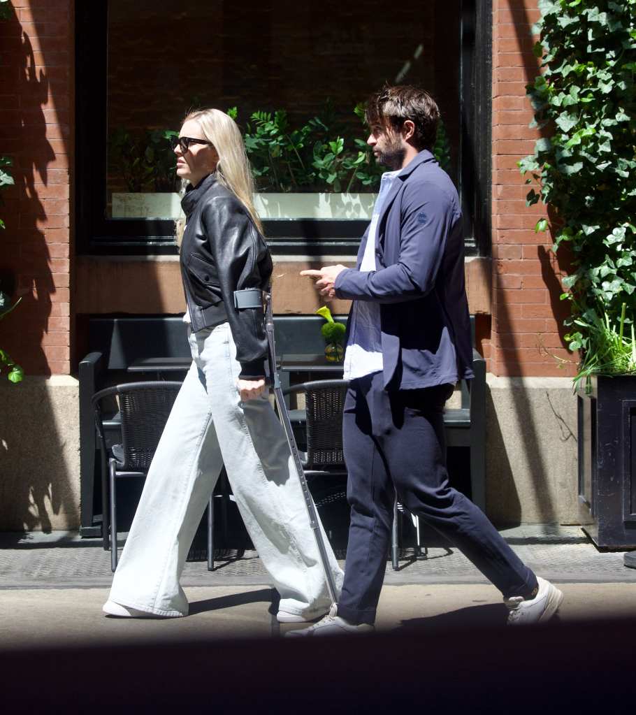 Lindsey Vonn walking with crutches beside Matthieu Bailet in New York City.