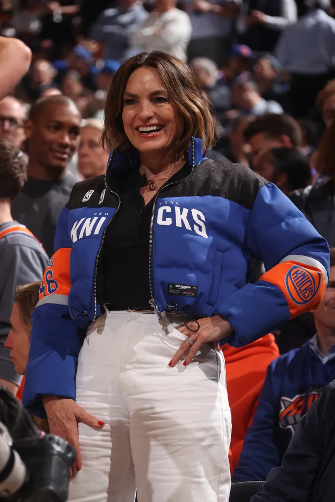 Mariska Hargitay smiles while wearing a blue, black, and orange New York Knicks jacket.