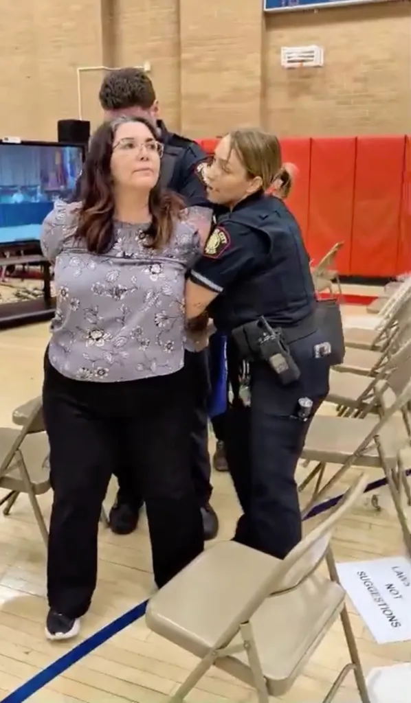 Police officers arrest parent Emily Pecot at the Jersey City Board of Education meeting.
