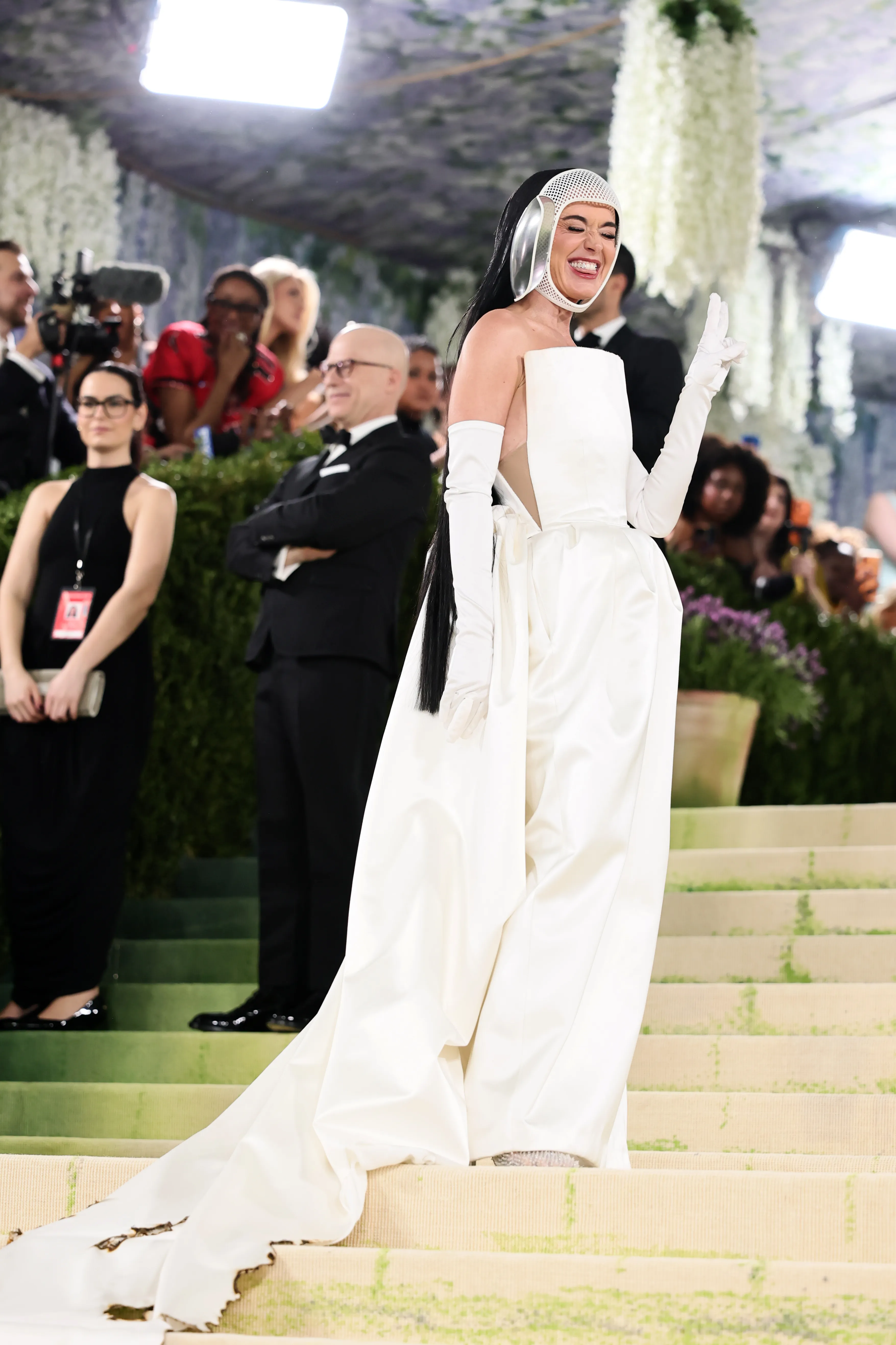 Katy Perry in a white strapless gown and a matching white headpiece and long gloves.
