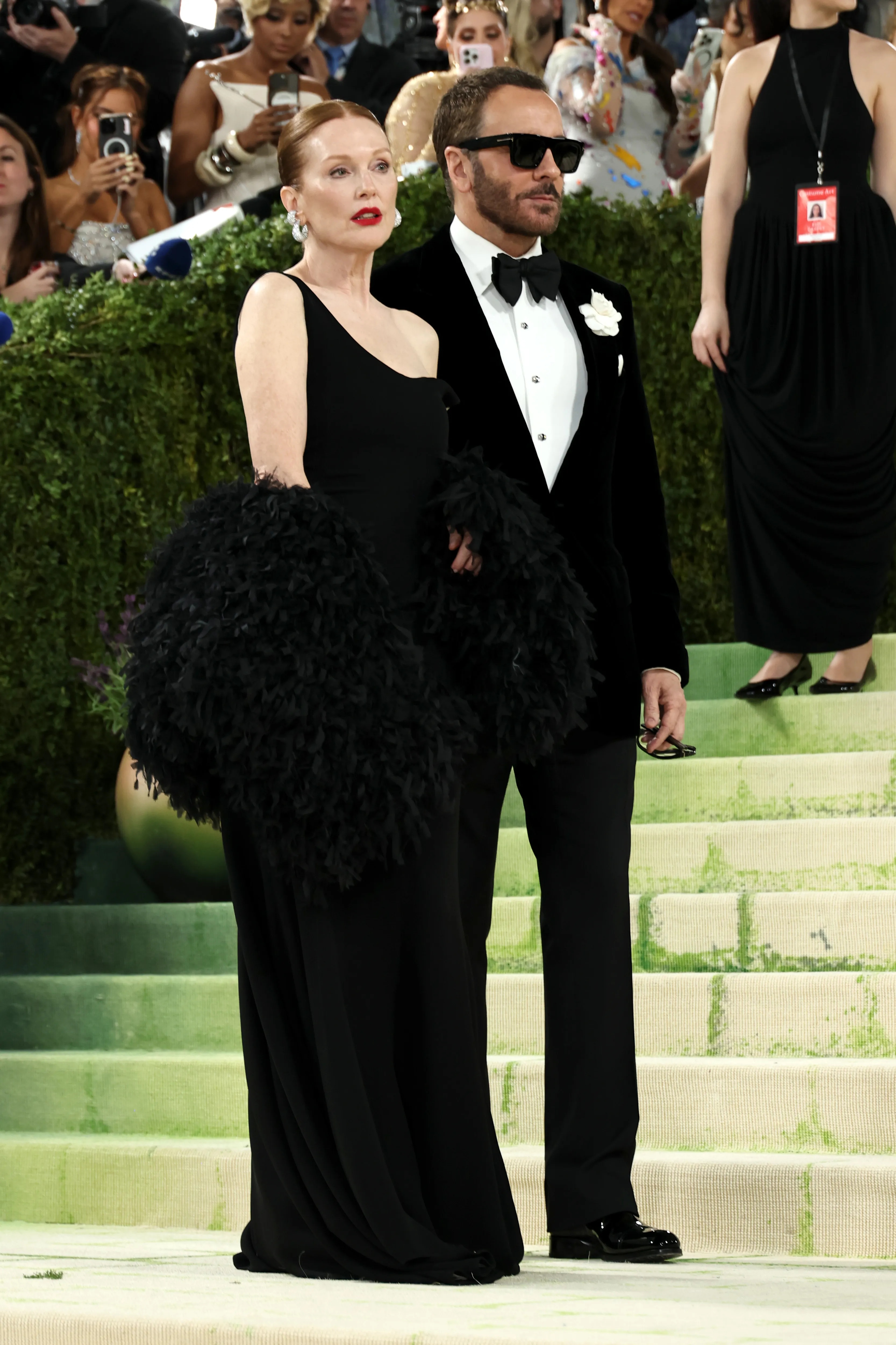 Julianne Moore in a black gown and feathery stole and Tom Ford in a black velvet tux and sunglasses at the 2026 Met Gala.