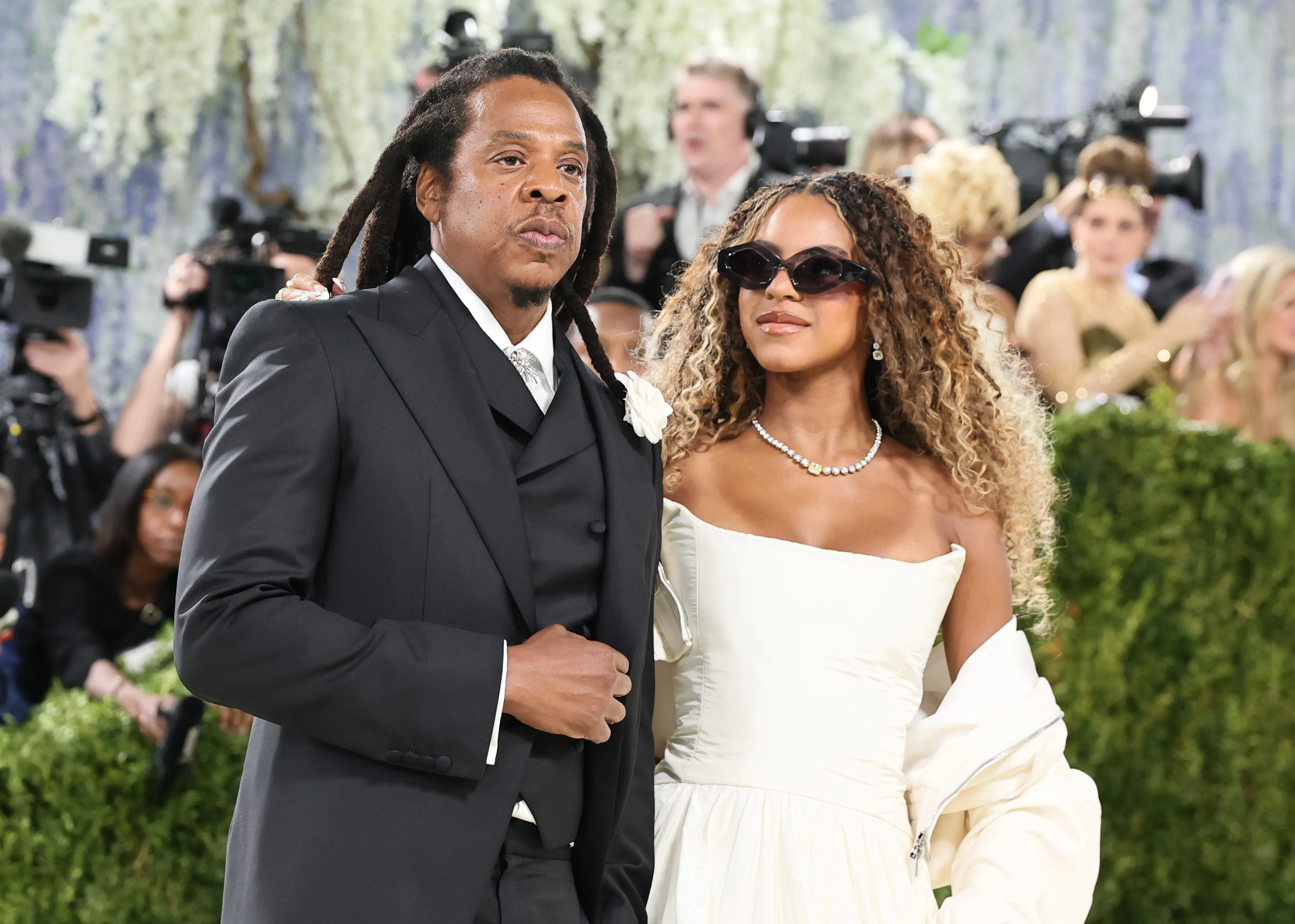 Jay-Z, in a black suit with a white flower on his lapel, and Blue Ivy Carter, in an off-white gown and sunglasses, pose for a photo at the Met Gala.