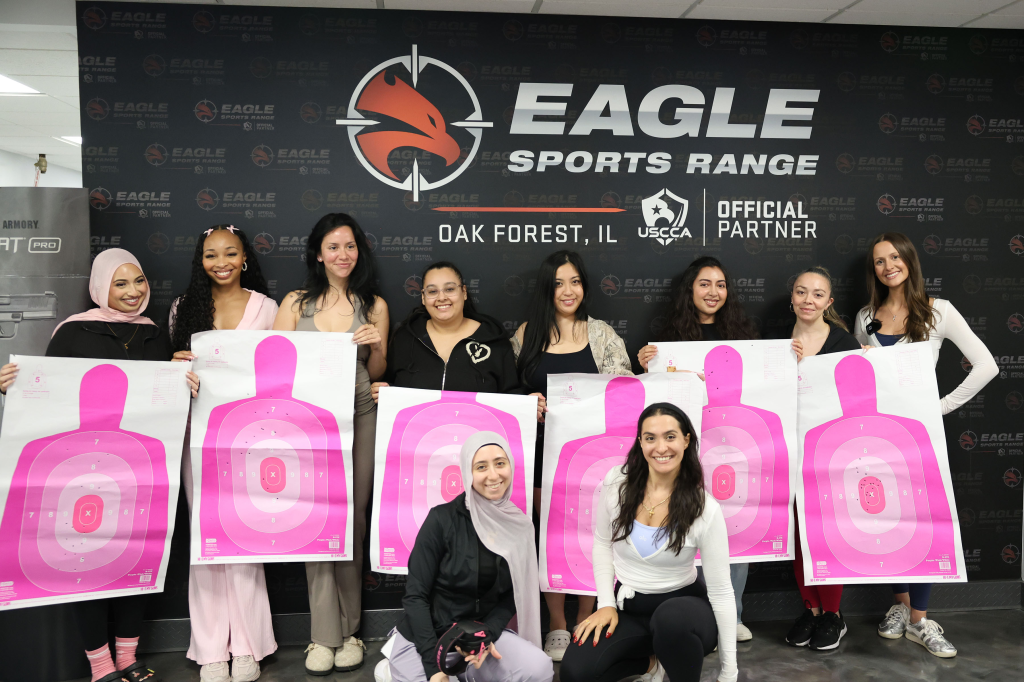 Nine women pose with pink shooting targets at Eagle Sports Range in Oak Forest, Illinois.