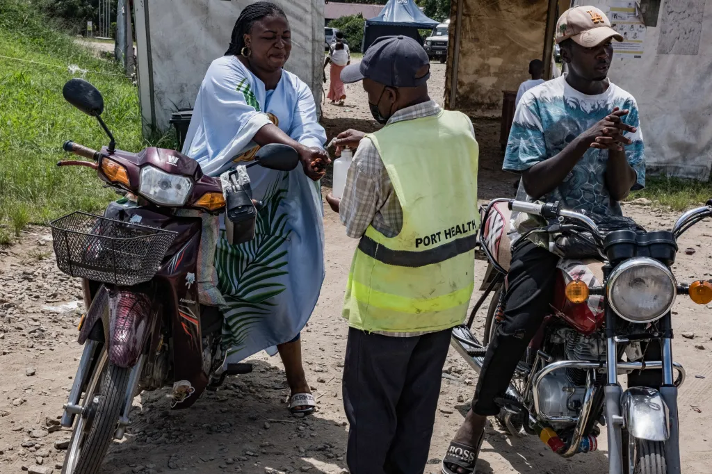 A port health officer sanitizes the hands of a woman at the Uganda-Democratic Republic of Congo border.