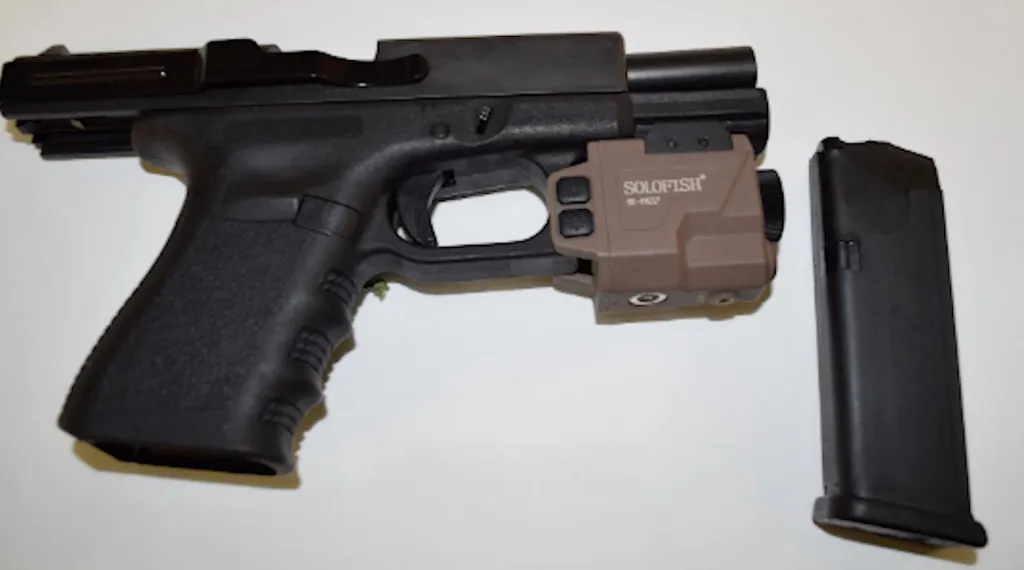 A black handgun with a tan SOLOFISH attachment and a separate black magazine.