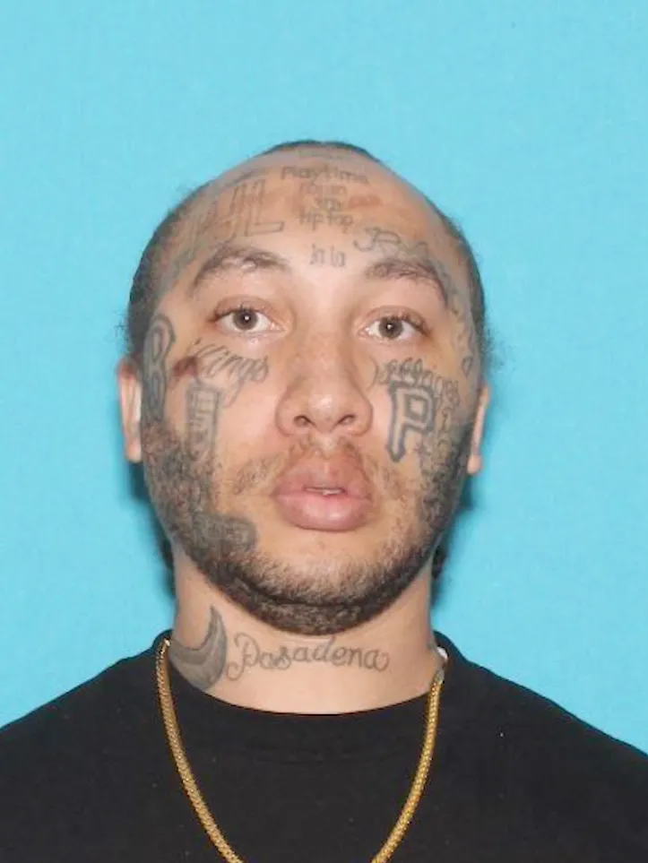 Mugshot of Malcolm Buchanan, a man with numerous facial and neck tattoos.