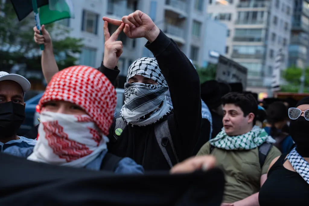 Antizionist protesters, many wearing keffiyeh scarves, outside Park East Synagogue.