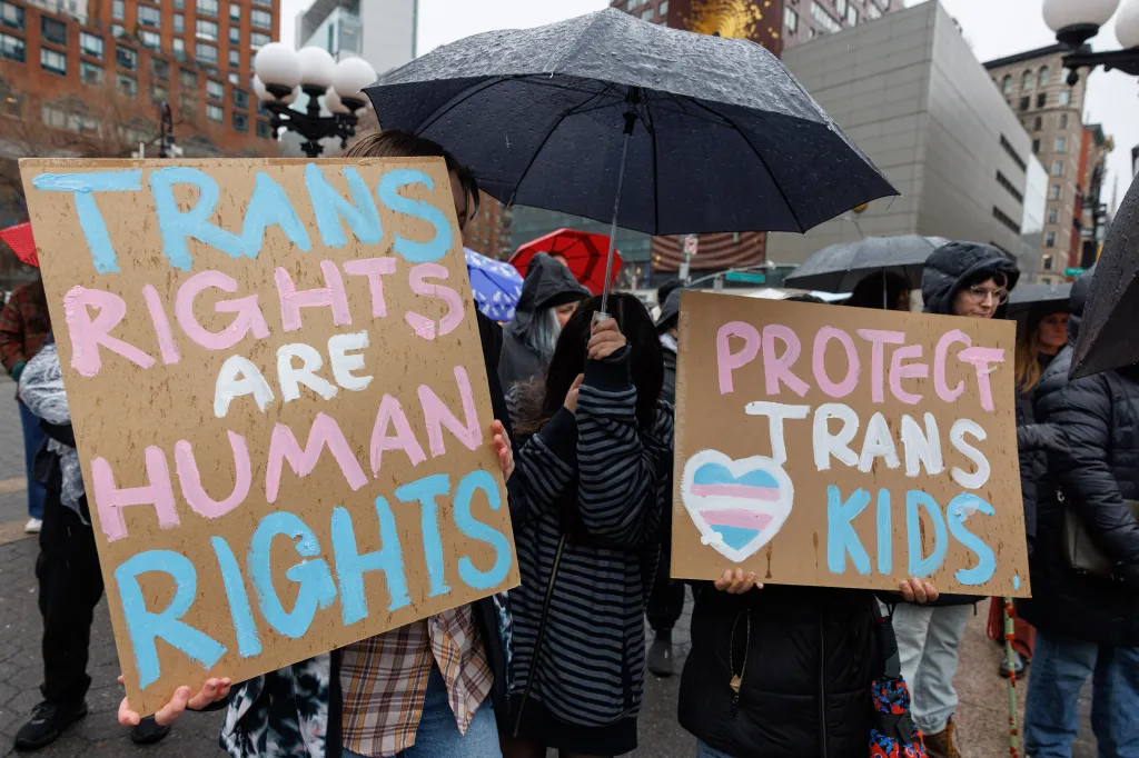 People at a rally hold signs that read, 