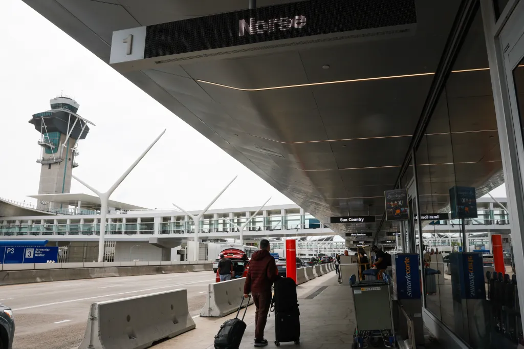 Airline passengers walk beneath a sign for Norse Atlantic Airways at Los Angeles International Airport (LAX).
