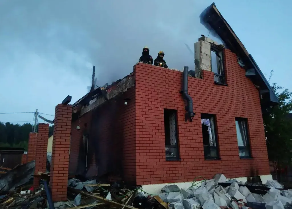 Russian rescuers atop a heavily damaged brick house following an air attack.