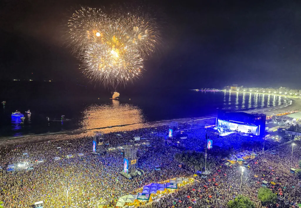 Shakira performs a free concert on Copacabana Beach, Rio De Janeiro, Brazil, at night, with fireworks lighting up the sky.