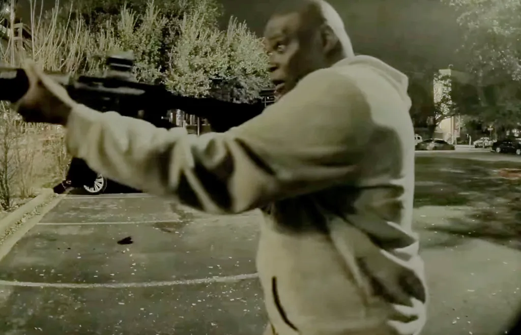 Ndiaga Diagne holding a rifle in a parking lot at night.