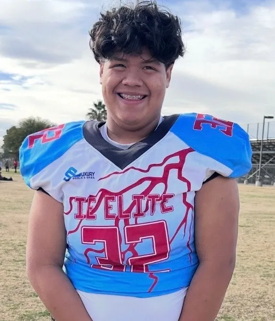 Jeremy Rosales, a young male football player, smiles at the camera while wearing a blue, white, and red jersey with the number 32.