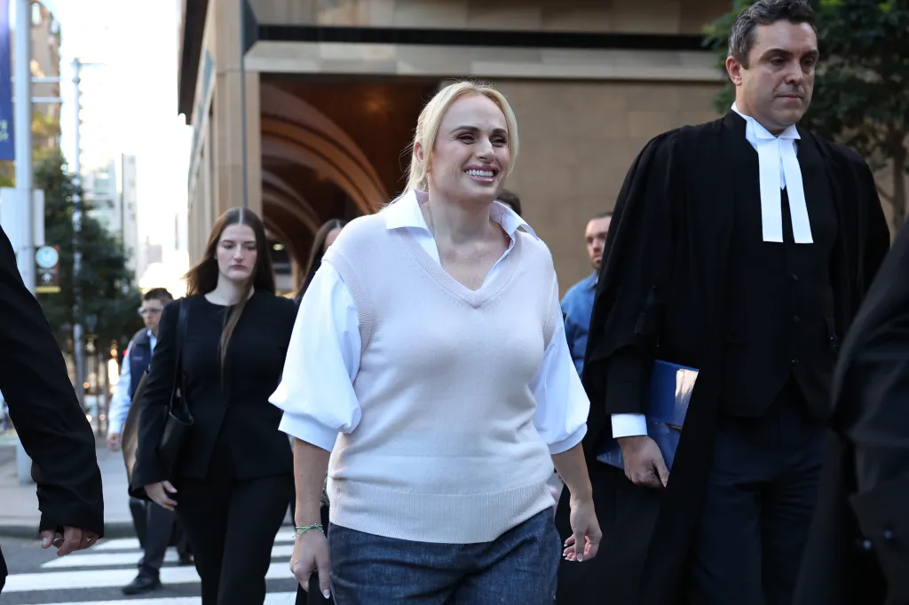 Rebel Wilson smiling as she walks with legal counsel to the Federal Court in Sydney for the defamation trial.