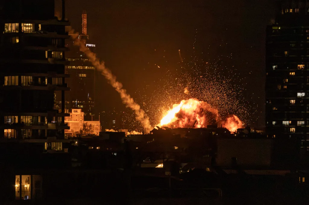 A large fireball and sparks light up the night sky over Tel Aviv during a missile strike.