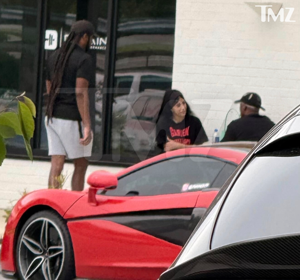 Cardi B and Stefon Diggs outside a cafe with a red sports car.