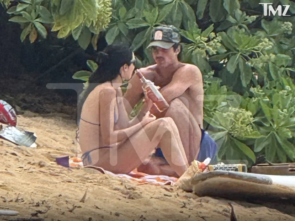 Kendall Jenner and Jacob Elordi sitting on a beach with drinks.