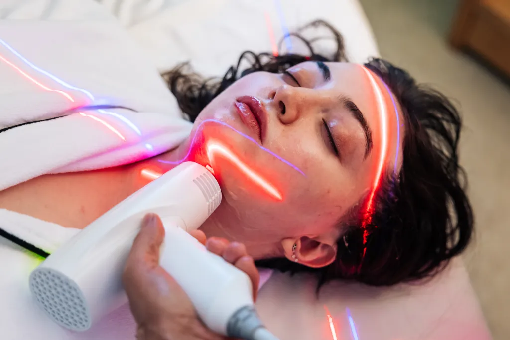A woman receiving a light therapy facial treatment.