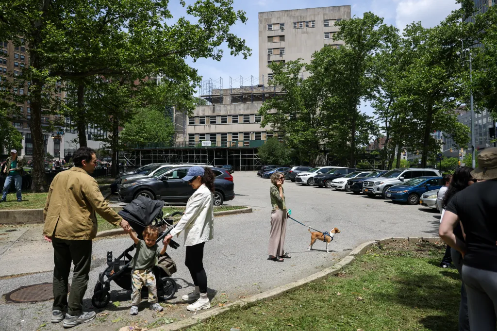 People walking in Columbus Park, with a building undergoing redevelopment in the background.