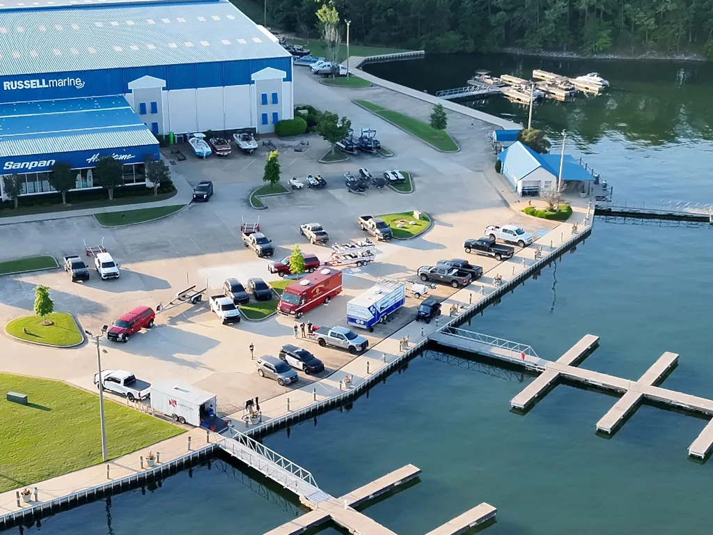 An aerial view of the Russell Marine facility at Lake Martin, showing multiple emergency vehicles, including an ambulance, on the docks.