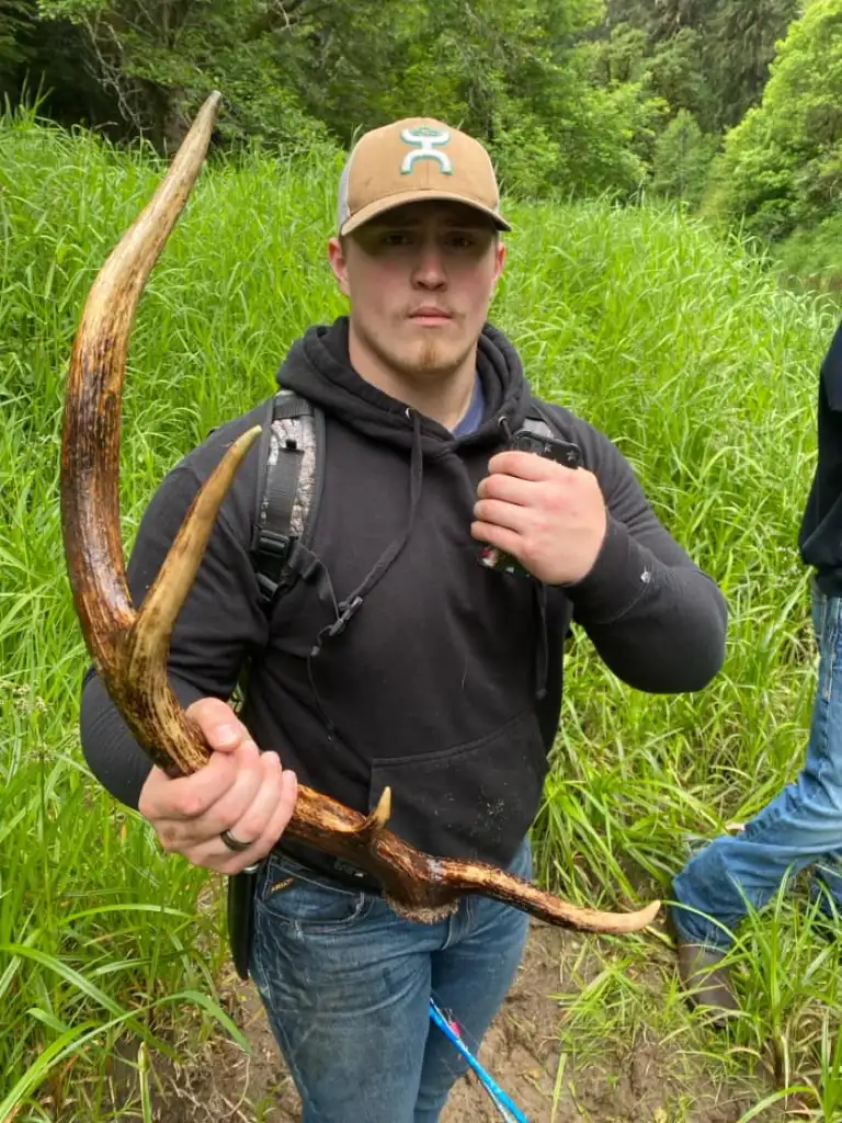 Man holding a large antler he found.